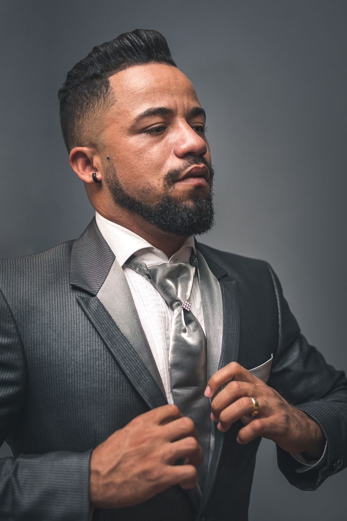 Crafting Captivating Headlines: Your awesome post title goes here Formal portrait of a bearded man adjusting his tie in a gray suit against a plain backdrop.